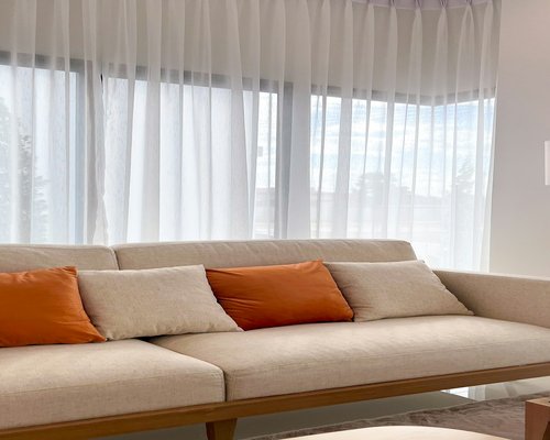 Window with sheer curtains filtering strong sunlight into a room